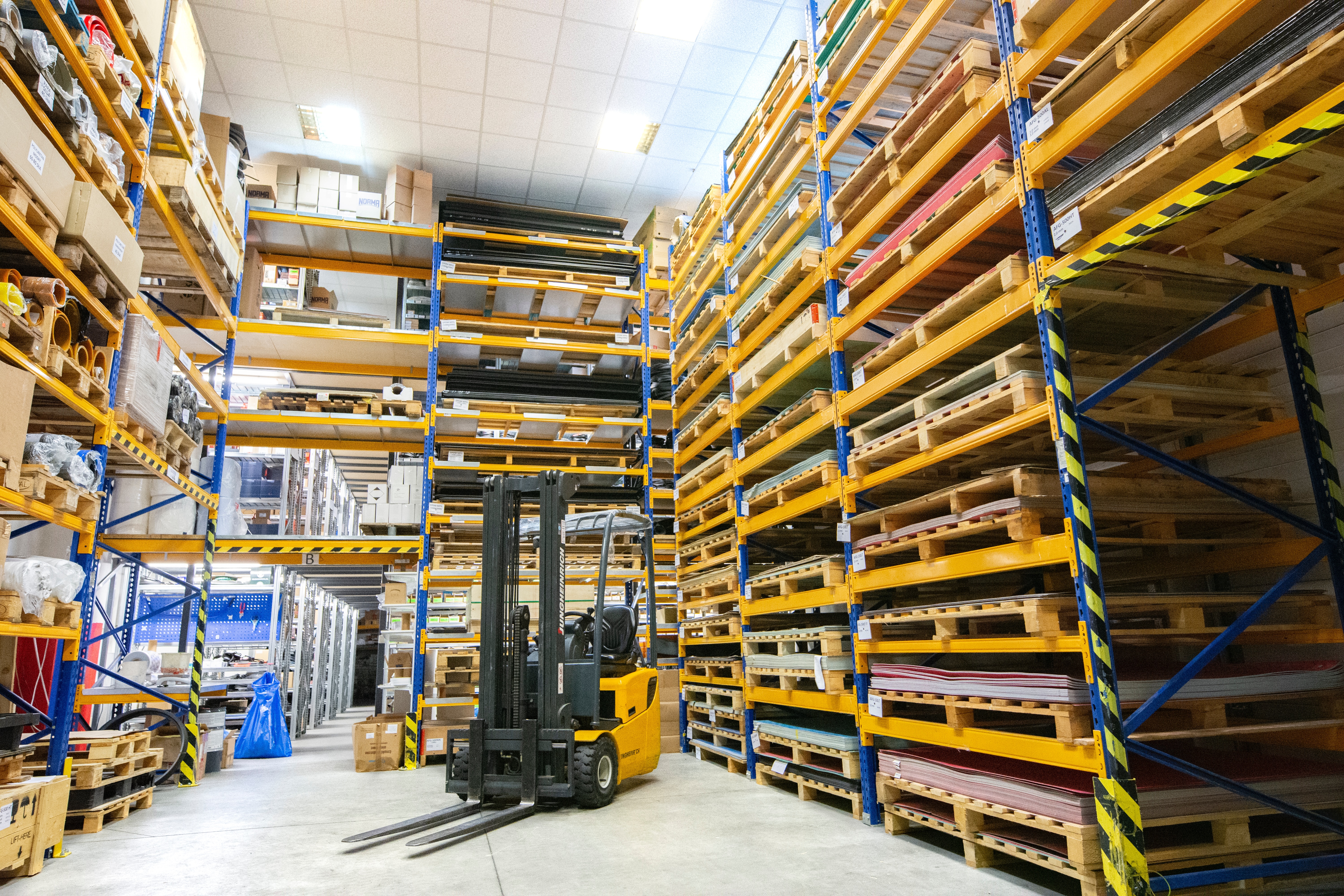 Forklift inside a warehouse surrounded by stock